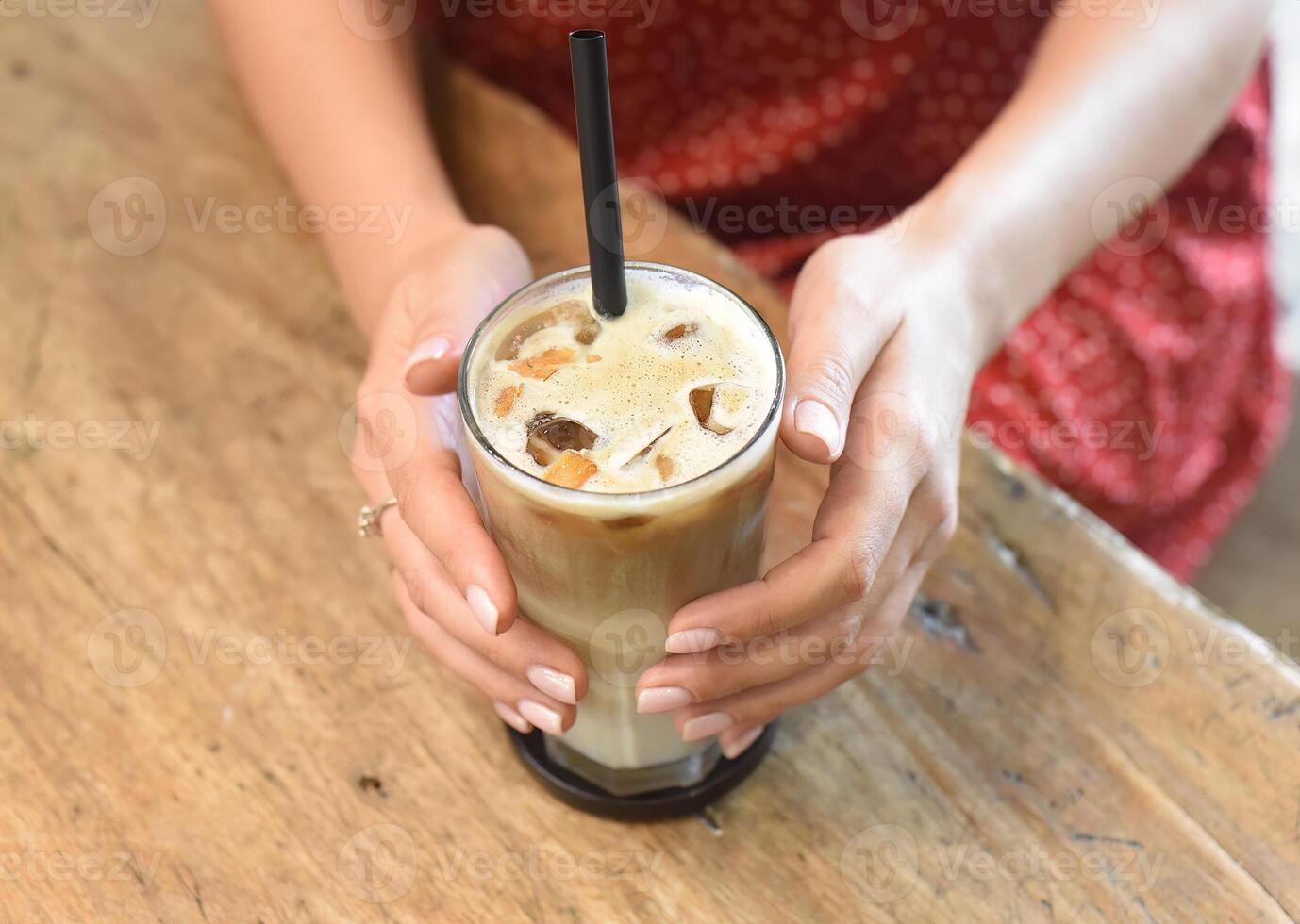 Woman's hands holding a glass of ice coffee photo