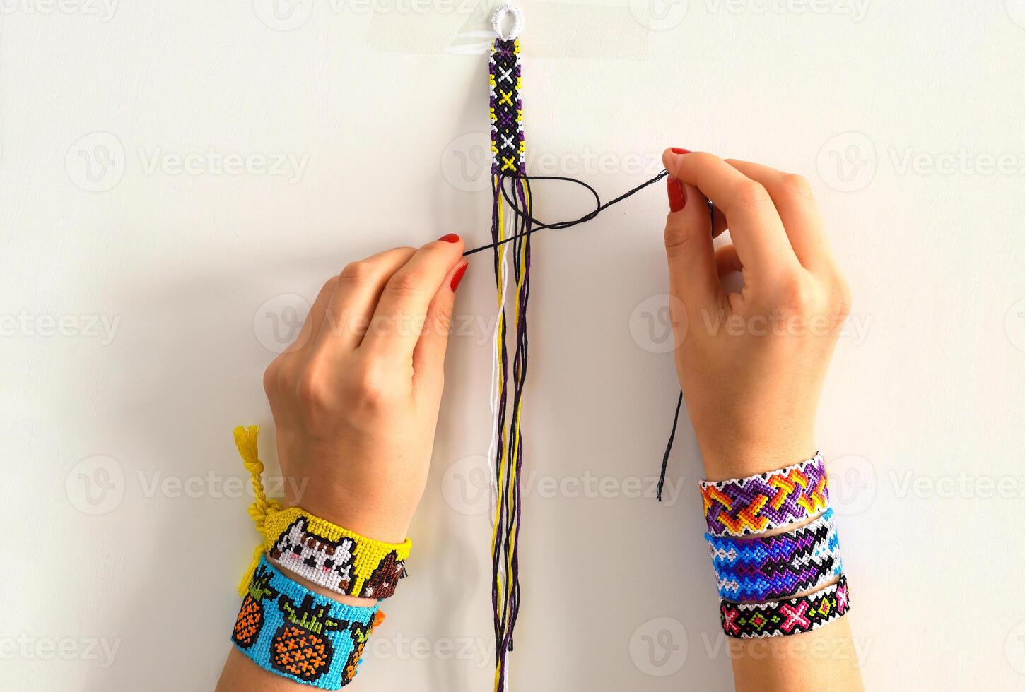 The process of weaving knot for DIY friendship bracelet. Female hands with many handmade bracelets on wrists. step by step. photo