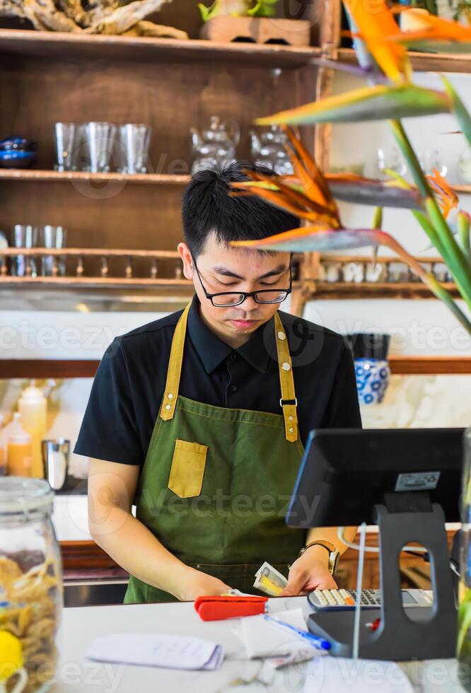 Vietnamese waiter working in counter with cashier machine in cafe photo