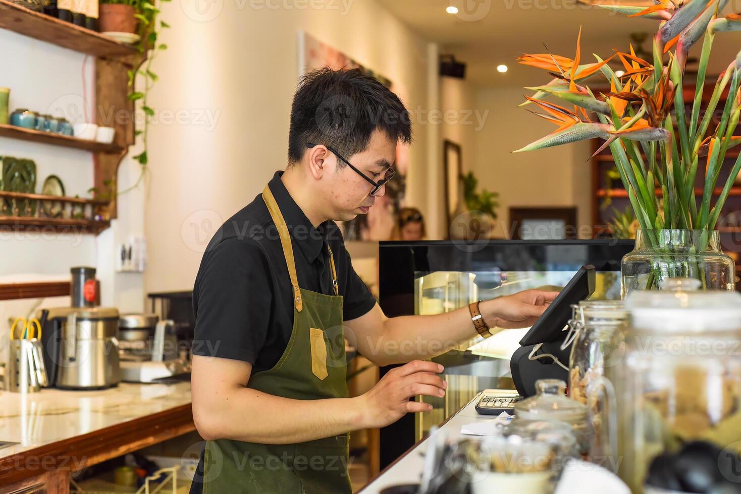 Vietnamese waiter working in counter with cash machine in a cafe photo