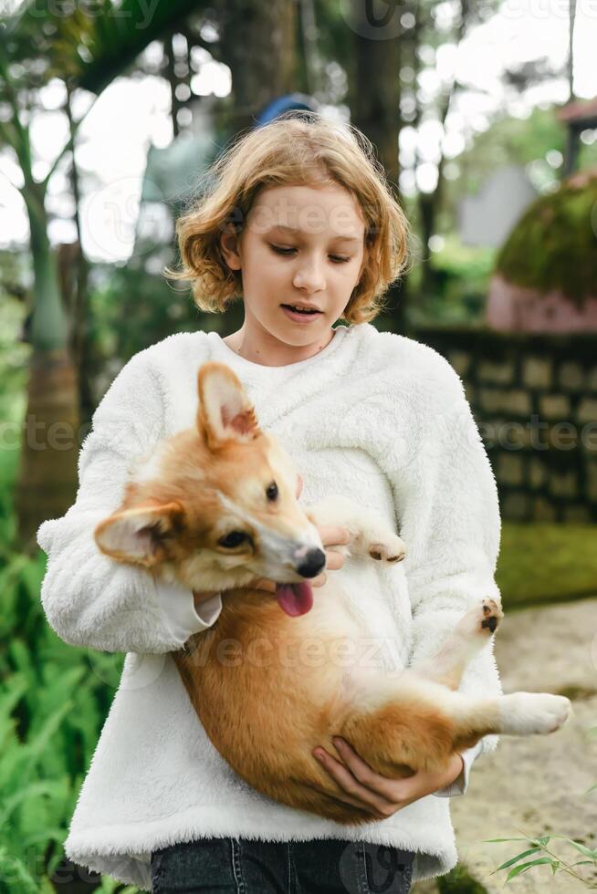 Little cute girl holding her corgi dog on autumn day photo