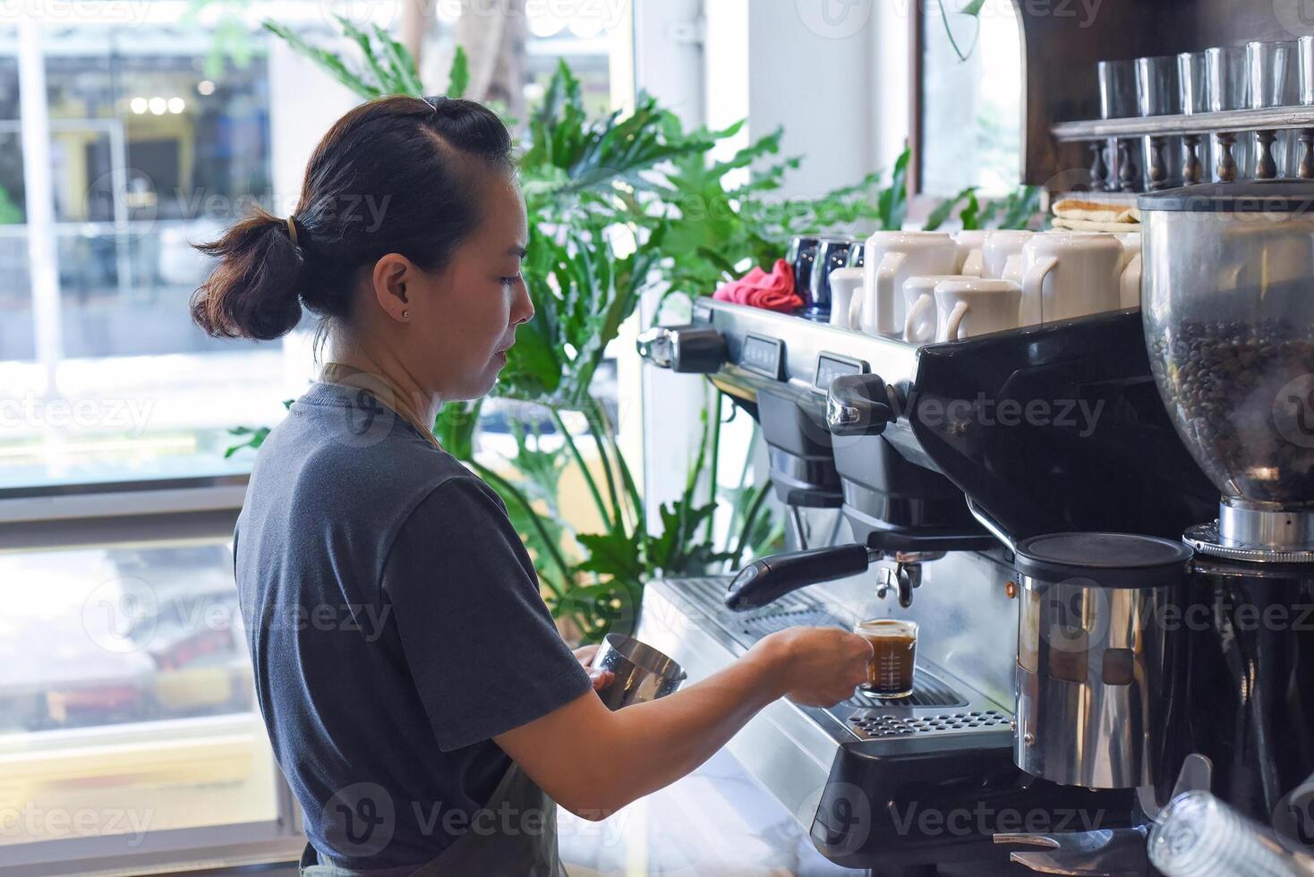 Vietnamese barista making espresso with coffee machine close up photo