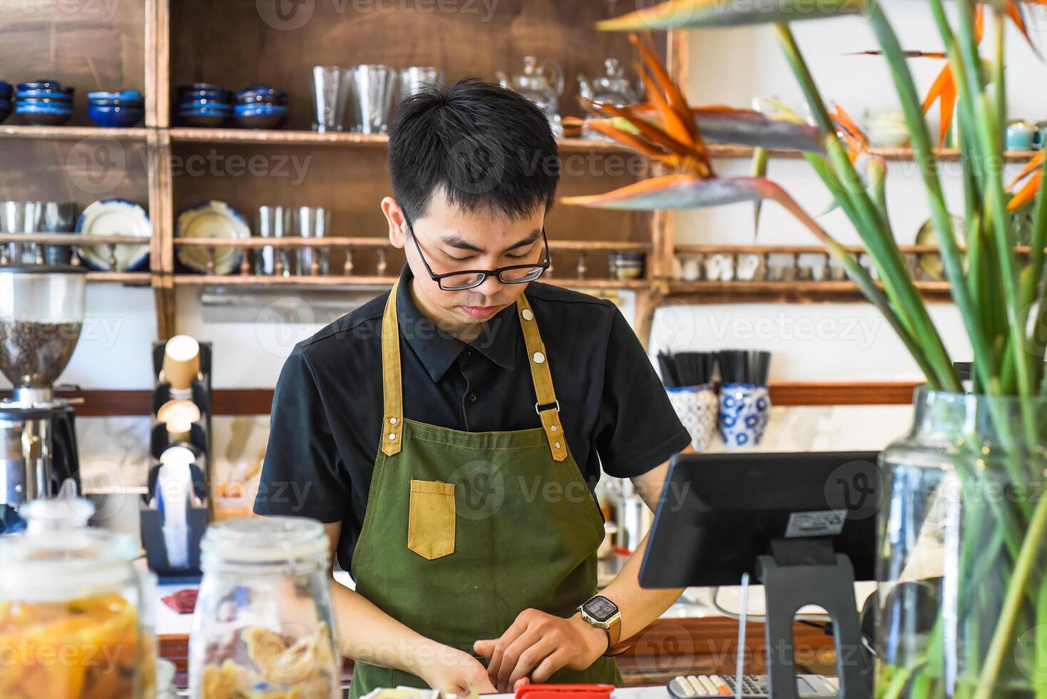 Vietnamese waiter working in a counter with cashier machine in a cafe photo