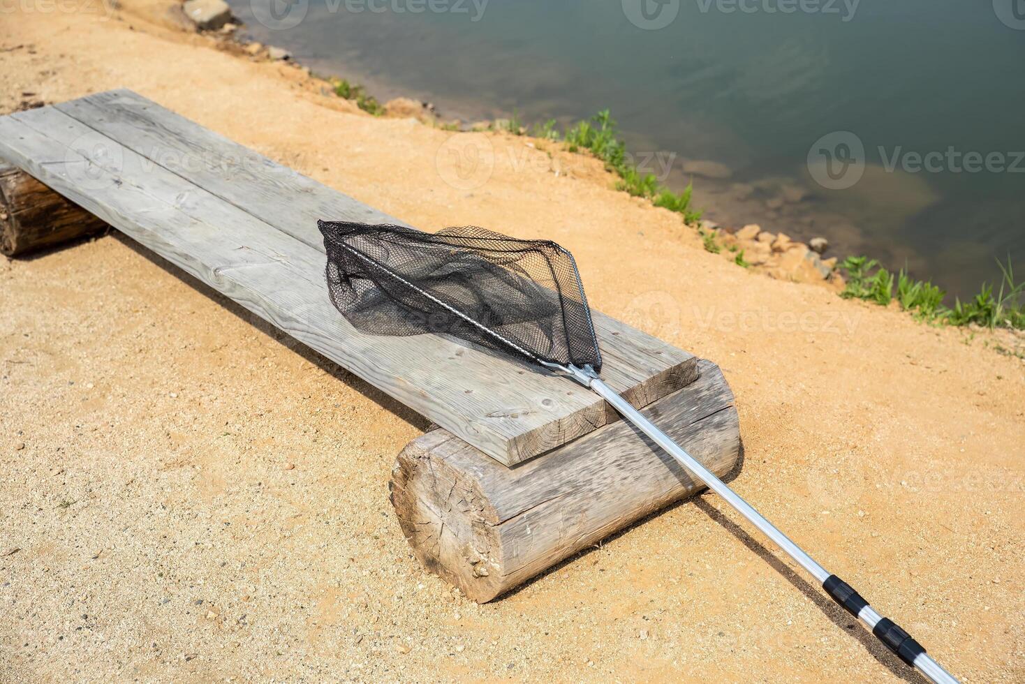 fishing net for fishing on the wooden bench against the backdrop of a pond.summer activities photo