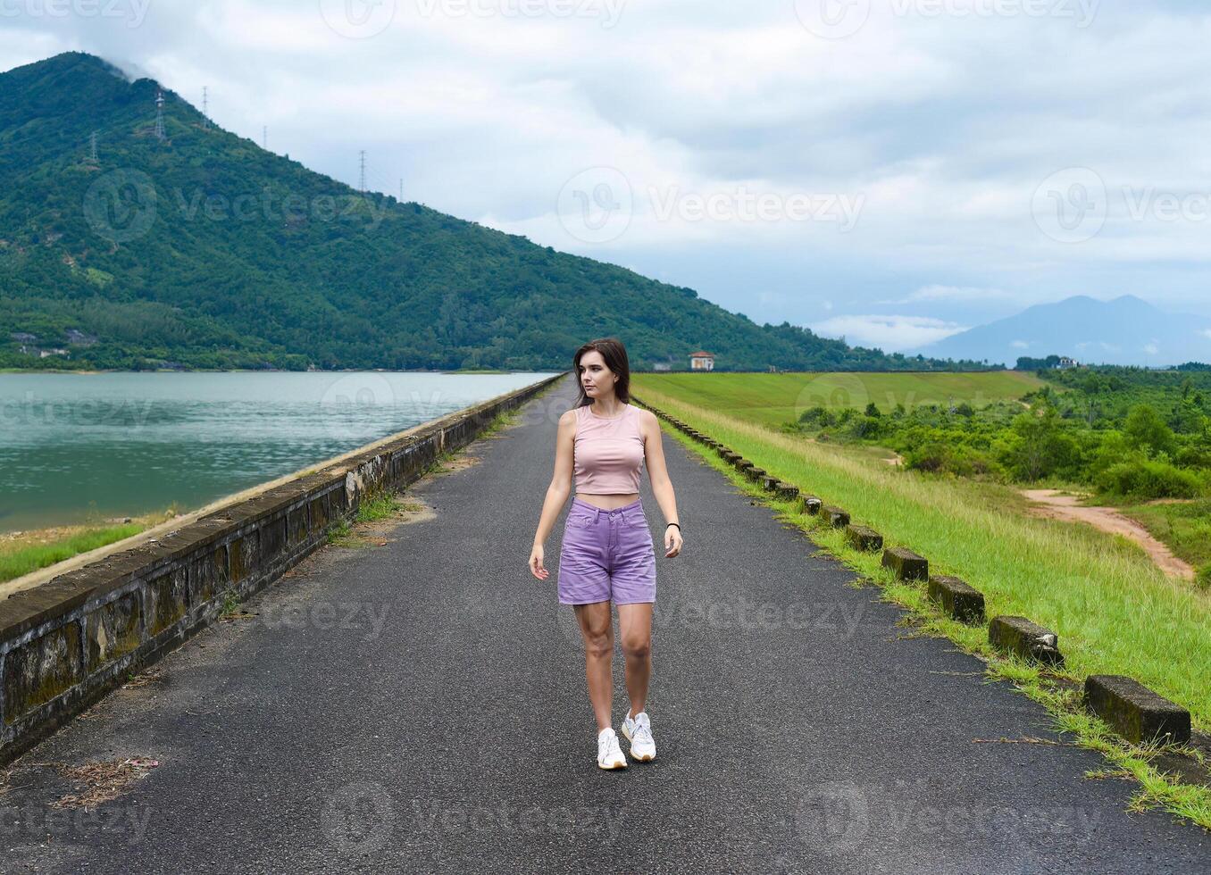 Young russian woman traveler with depressed and sad face walking alone near lake and mountains in Khanh Hoa Province, Vietnam photo
