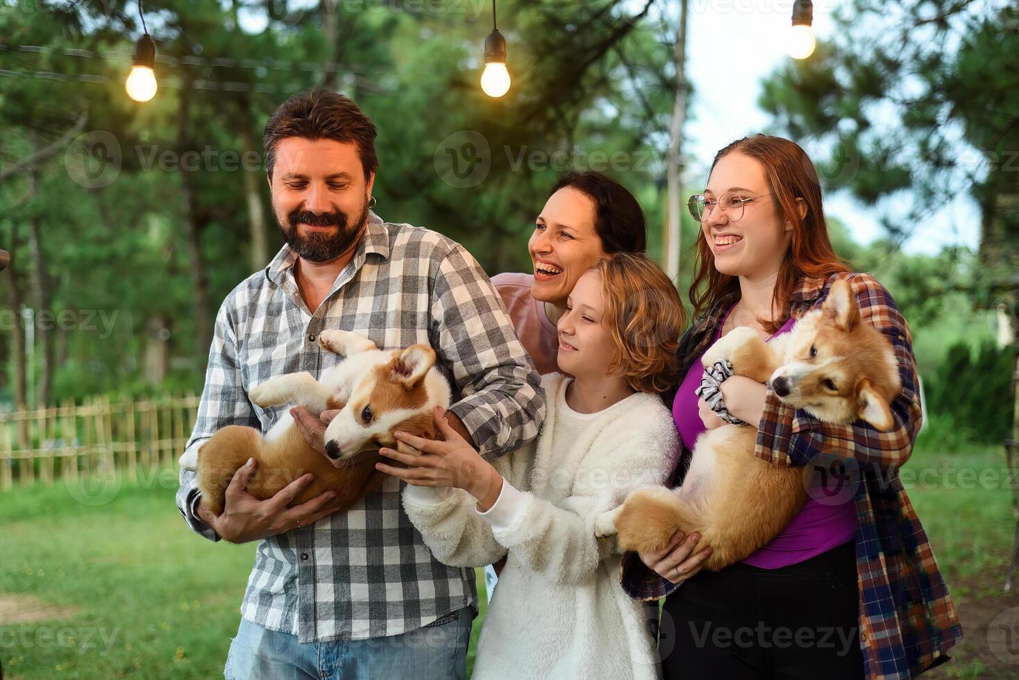 Family members father mother and two daughter with corgi dogs in the forest photo
