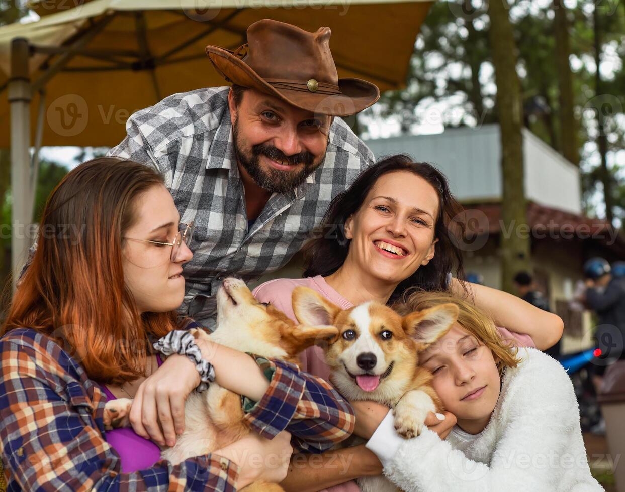 Family members father mother and 2 daughters with corgi dogs in the forest photo