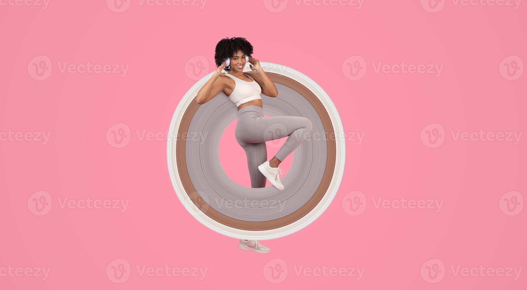 A playful and energetic African American lady in sporty attire winking and posing in a fun, isolated on a pink background photo