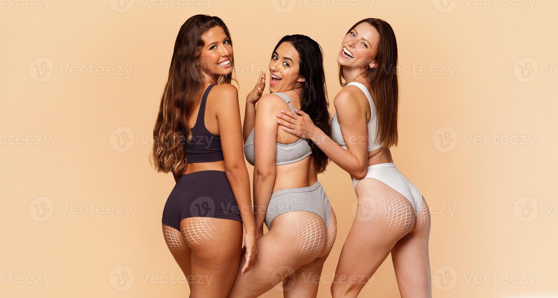 Three diverse women showcase their curves and confidence while engaging in body sculpting and skin care activities. The warm backdrop emphasizes their femininity and promotes a message of self-love. photo