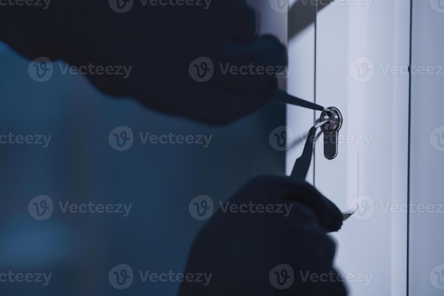Forced Entry. Closeup of unrecognizable intruder in black gloves unlocking door with master key photo