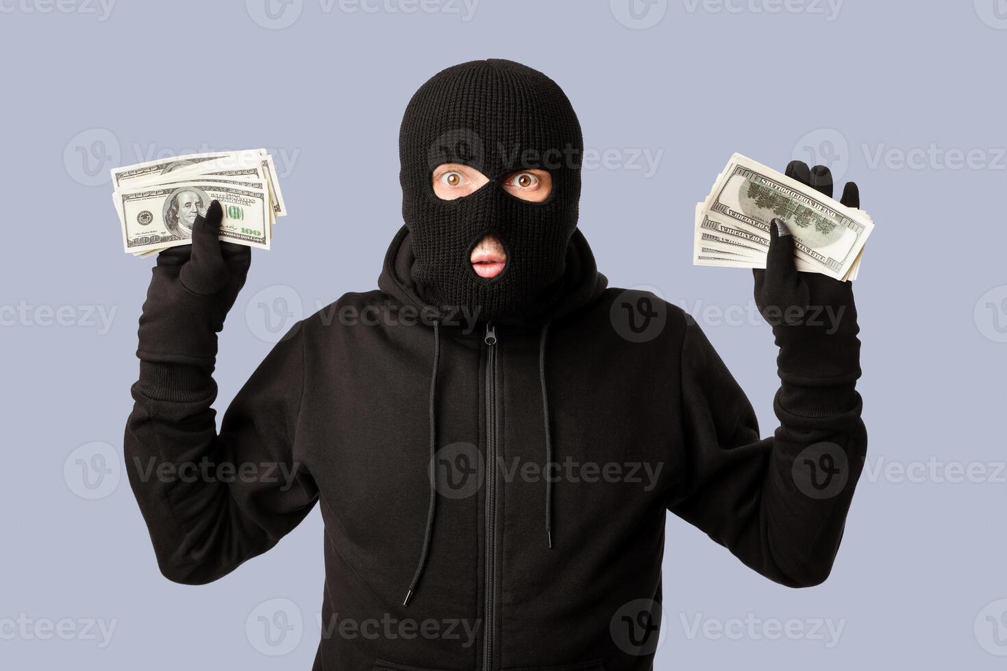 Hands Up. Masked robber being arrested by police for stealing money, standing isolated over white studio background photo