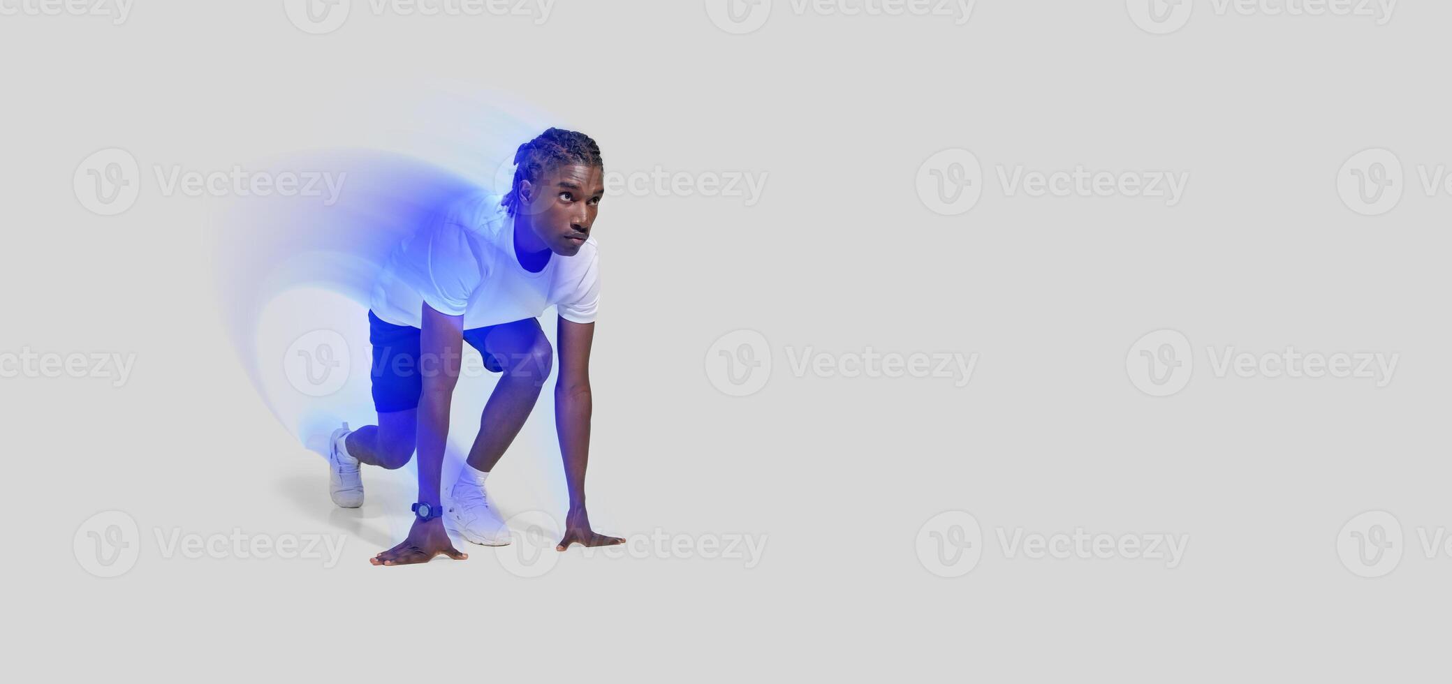 An african american athletic man is captured in a runner's starting position, isolated on a white backdrop photo