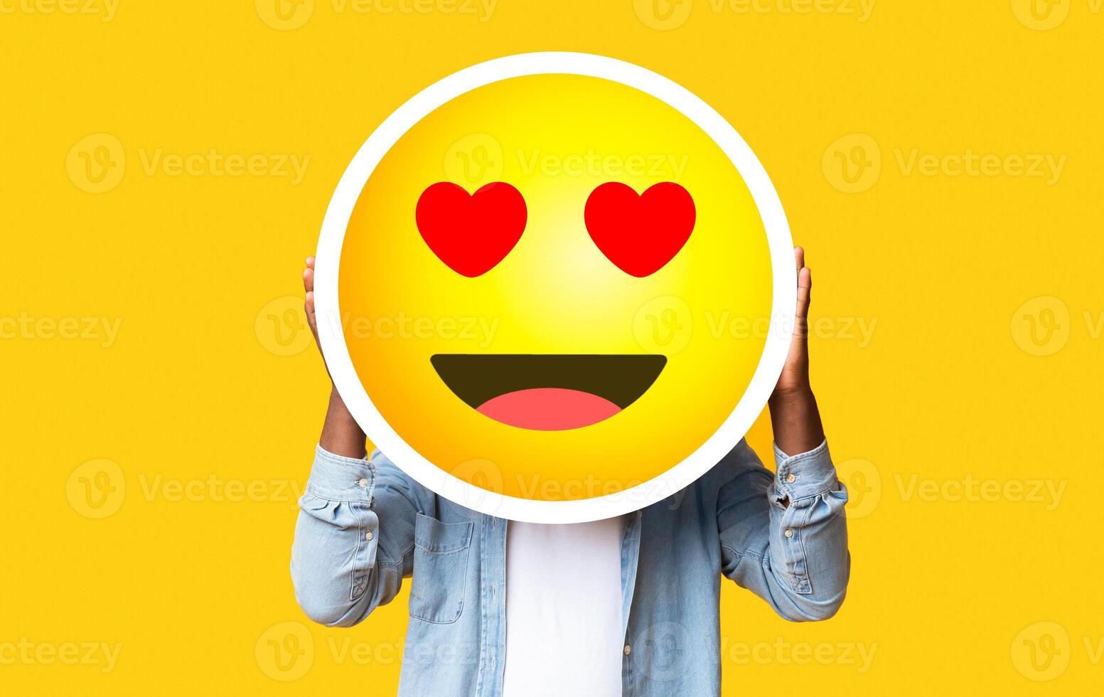 I Love Emoji. Unrecognizable Black Man Hiding Face Against Romantic Emoticon Sticker, Standing Over Yellow Background With Free Space photo