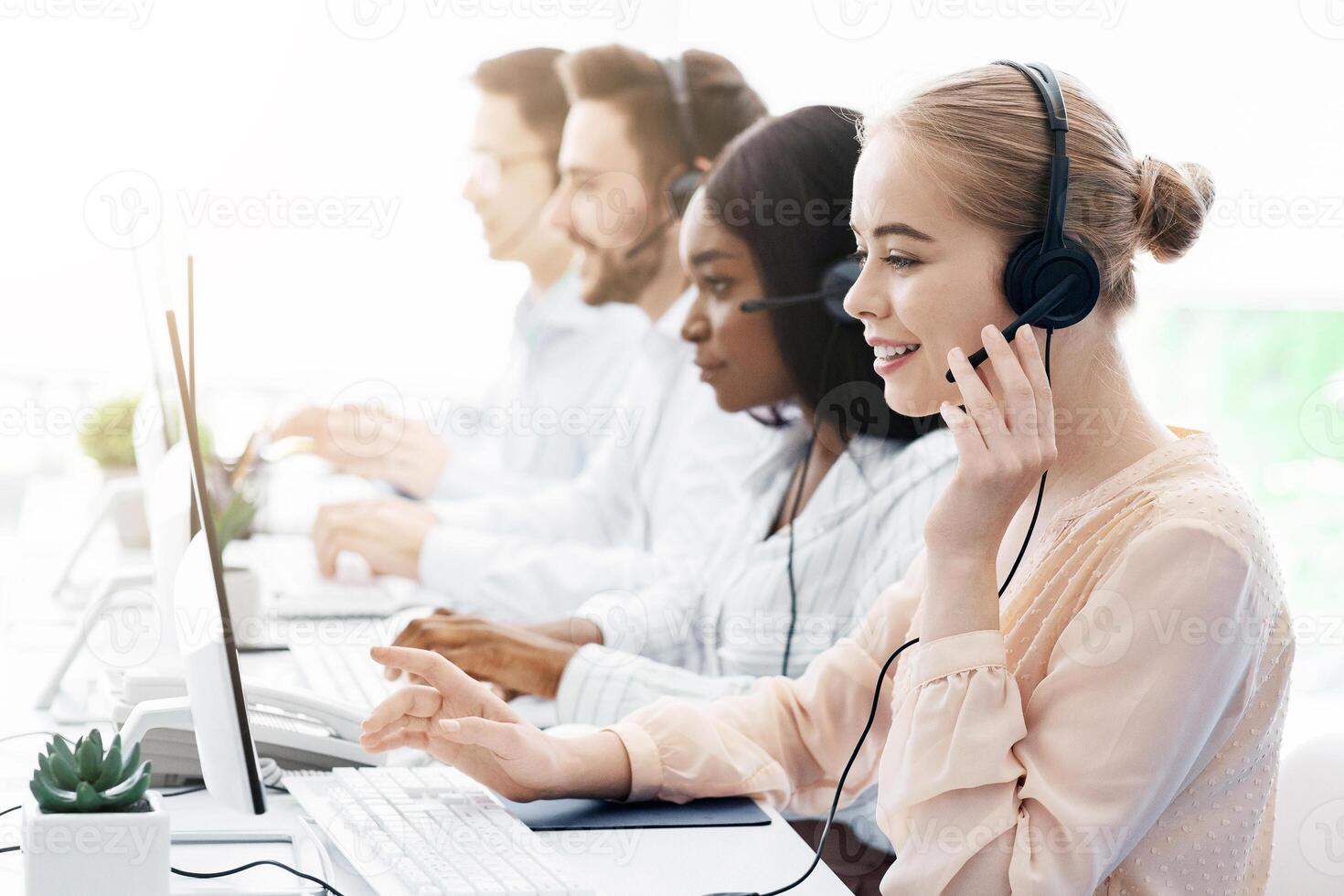 Team of helpline operators with headsets consulting clients at call center office, blank space photo