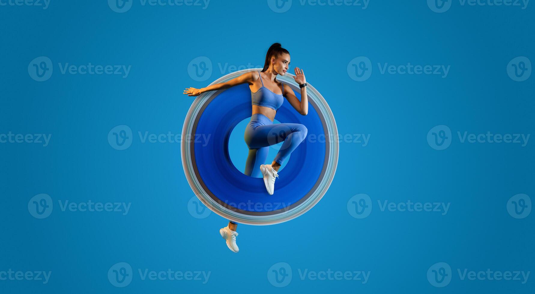 Woman Athlete Jumping Exercising During Training Over Blue Studio Background, Looking Aside. Fitness Workout And Sport Motivation Concept. Full Length, Side View photo