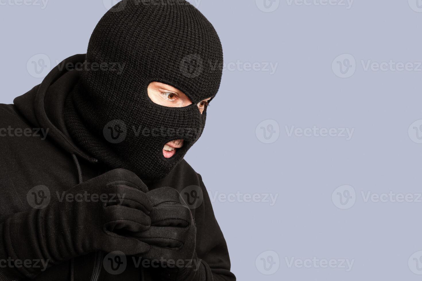 Closeup portrait of greedy disguised villain in black mask looking at something to steal, copyspace, white studio wall photo