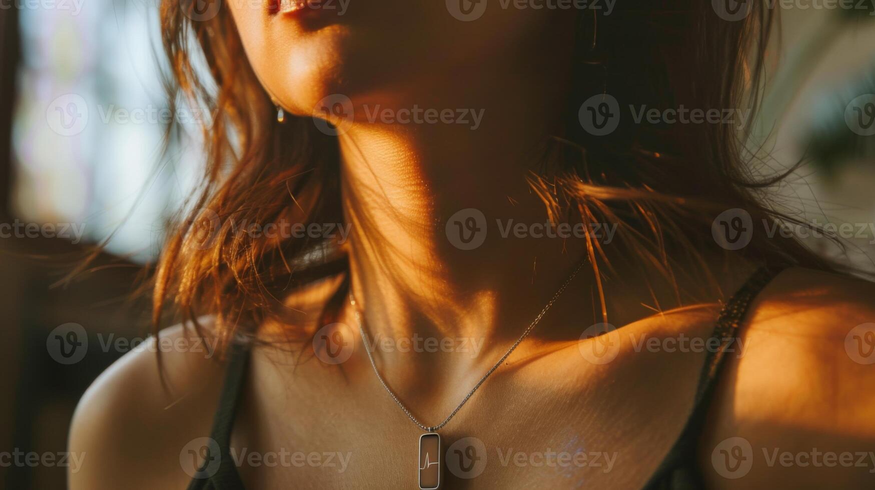 A woman poses with a delicate necklace as soft sunlight highlights her features in a warm, inviting indoor environment during the afternoon hours. photo