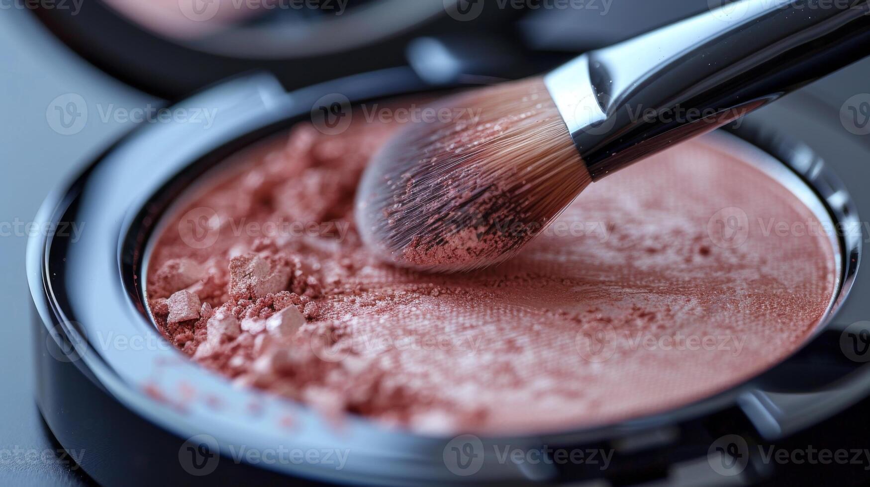 A close up view of a makeup brush picking up blush powder from a compact on a surface, showcasing the application process in a personal care environment. photo