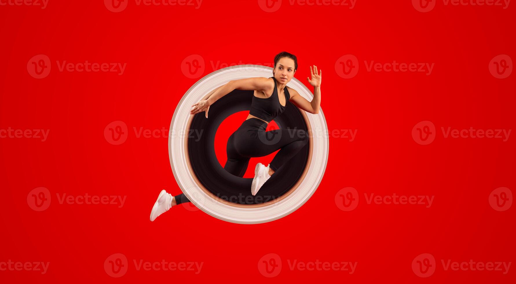 A woman wearing a black top and black leggings is captured mid-jump in the air. Her arms are outstretched and her legs are bent, showcasing her athleticism and agility as she defies gravity. photo