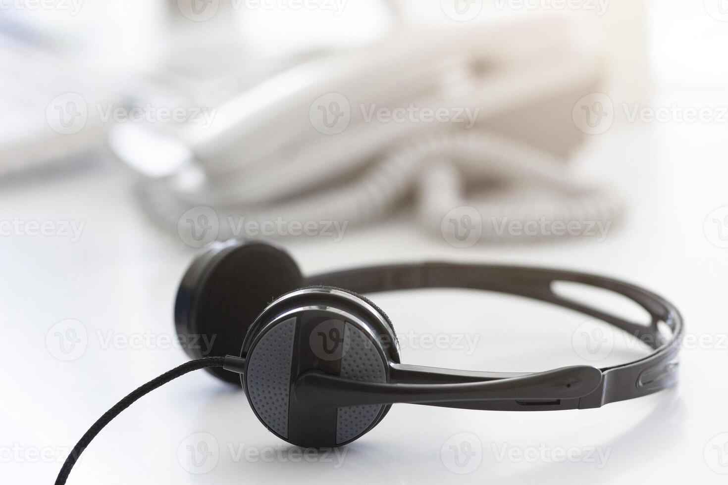 Helpline operator's workplace with modern headphones at call centre, empty space. Tech support manager's desk with headset. Telemarketing and telecommunications concept photo