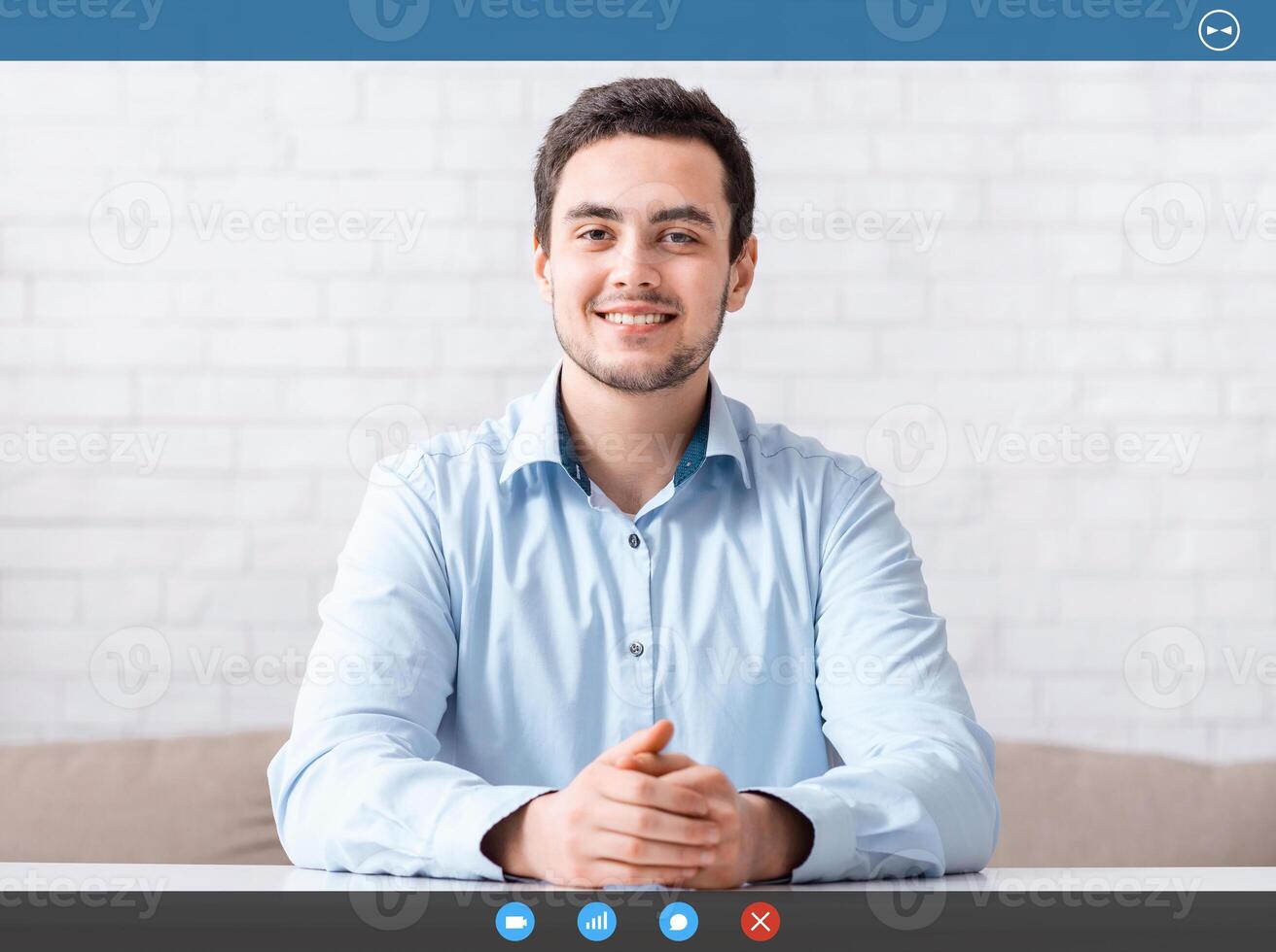 Online meeting and work from home. Smiling friendly guy in shirt with hands on table in living room interior, free space photo