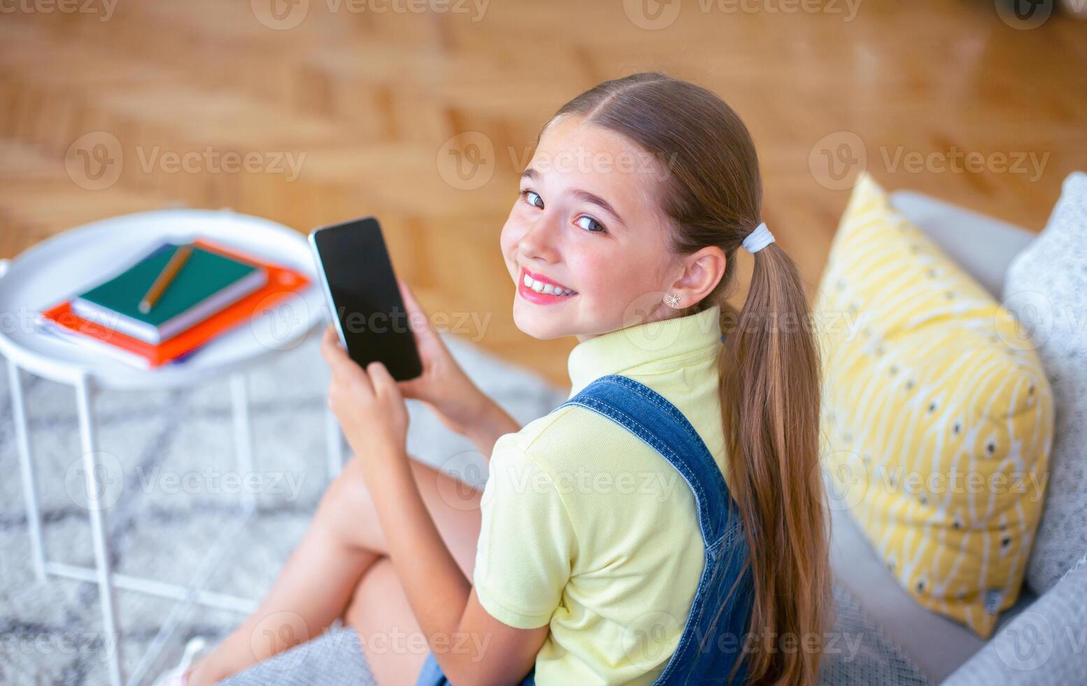 Over the shoulder view closeup portrait of girl using her cell phone with black screen, looking back at camera photo