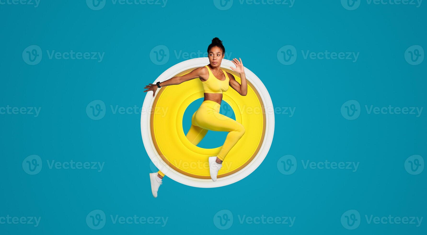 Determined African American fitness woman jumps against blue studio background, leaping and running in mid air during cardio exercises. Weight loss and vitality. Full length photo
