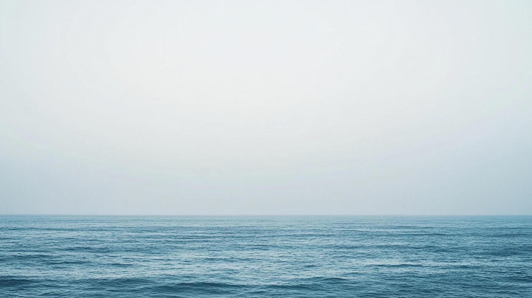 This minimalist image presents an expansive view of the ocean, shrouded in fog, creating a sense of mystery and reflection, perfect for thoughtful artwork. photo