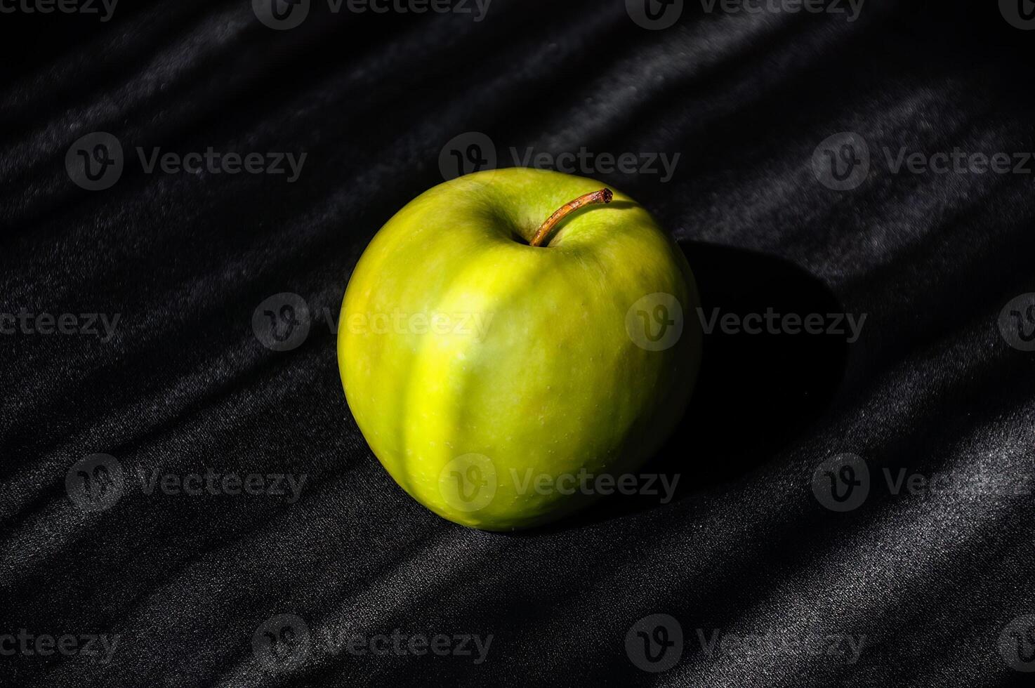 Big green apple on striped dark gray and light gray background photo
