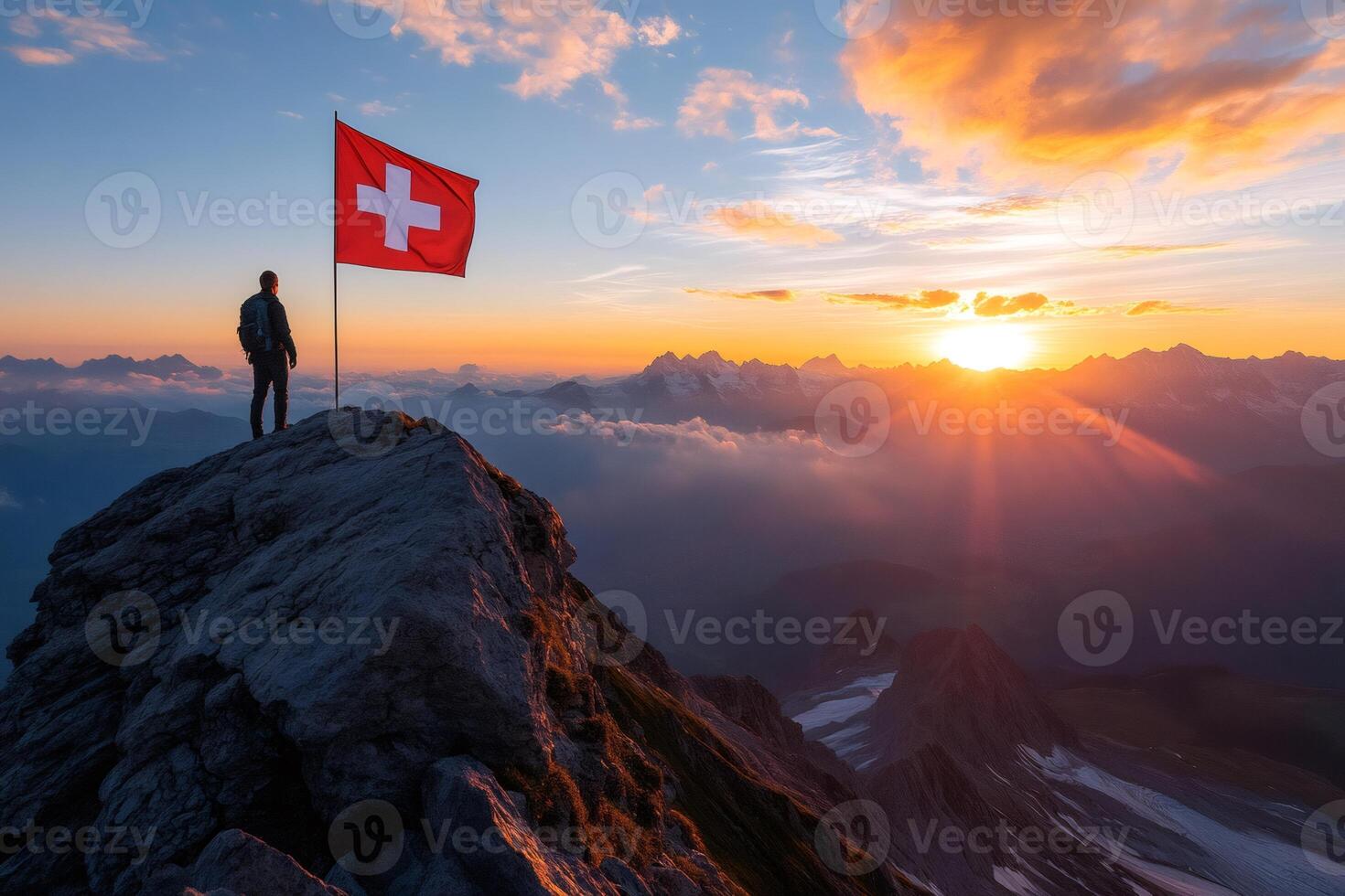 Mountaineer raising Swiss flag on mountain peak at sunrise photo