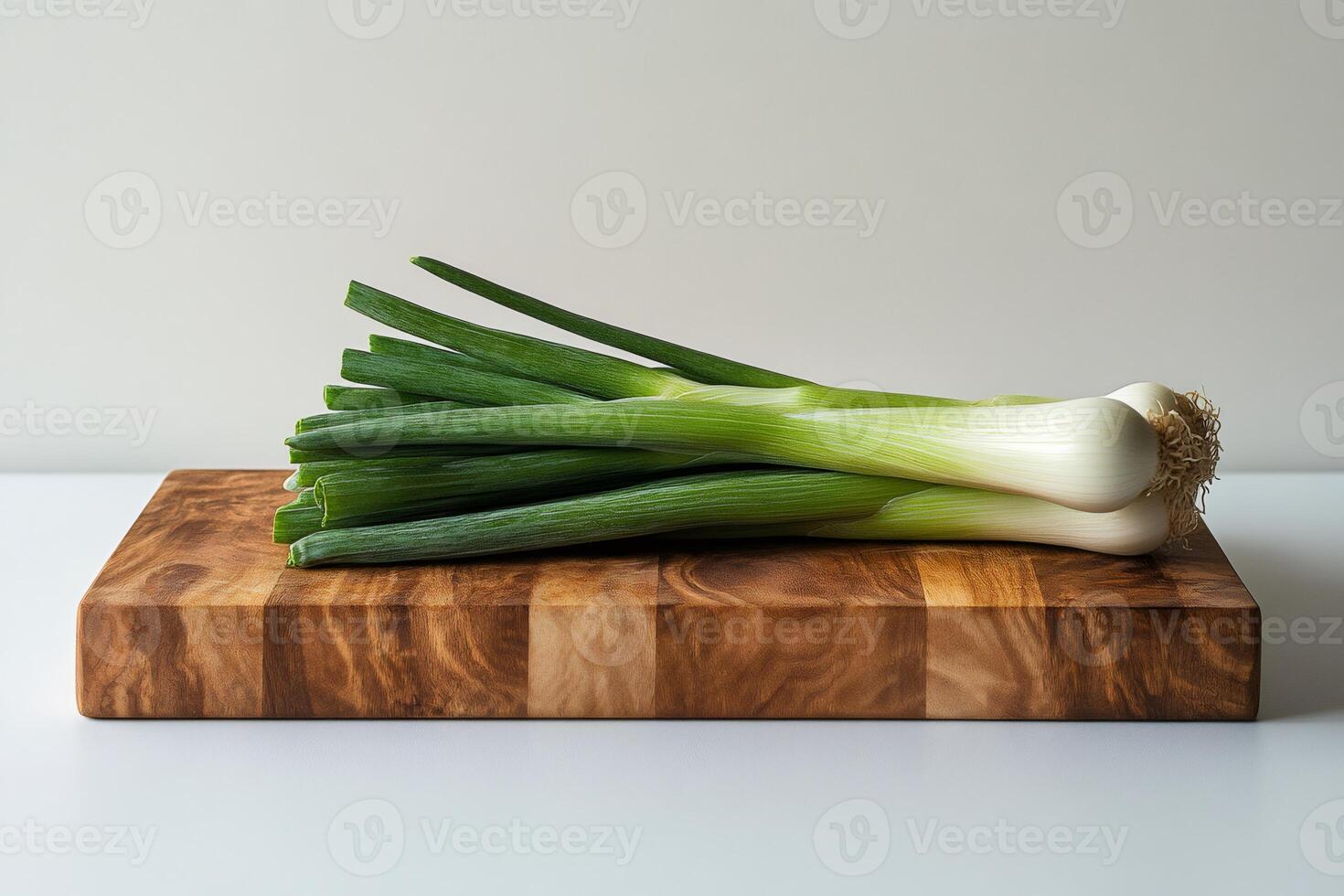 Bunch of fresh spring onions resting on a wooden cutting board photo