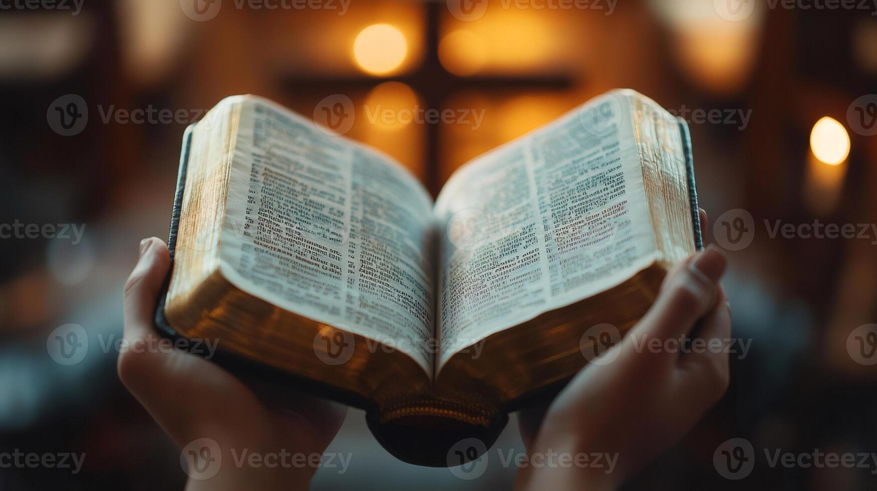 Hands holding open Bible in church, reading holy book against cross background photo