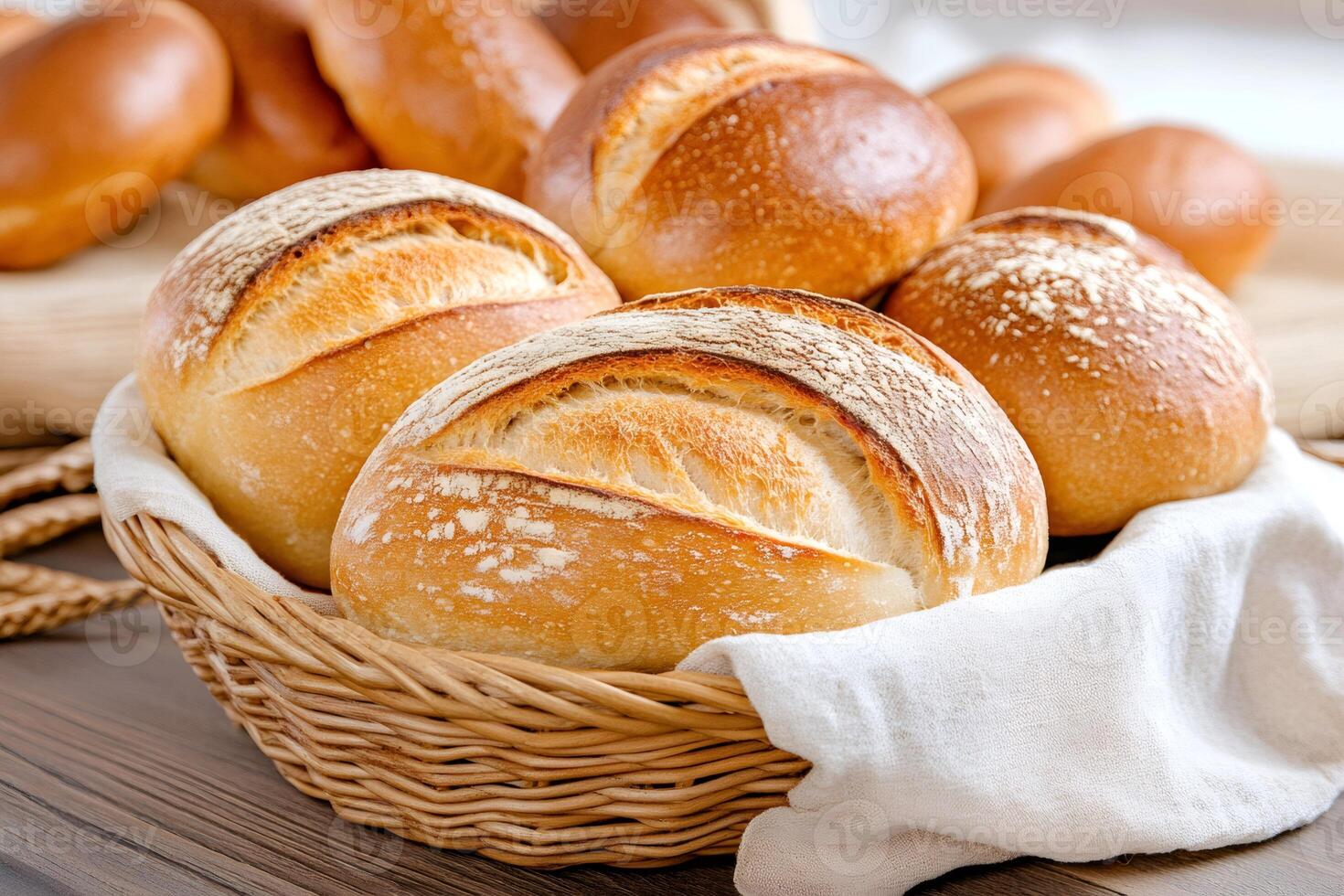 Freshly baked bread rolls resting in wicker basket with white cloth photo