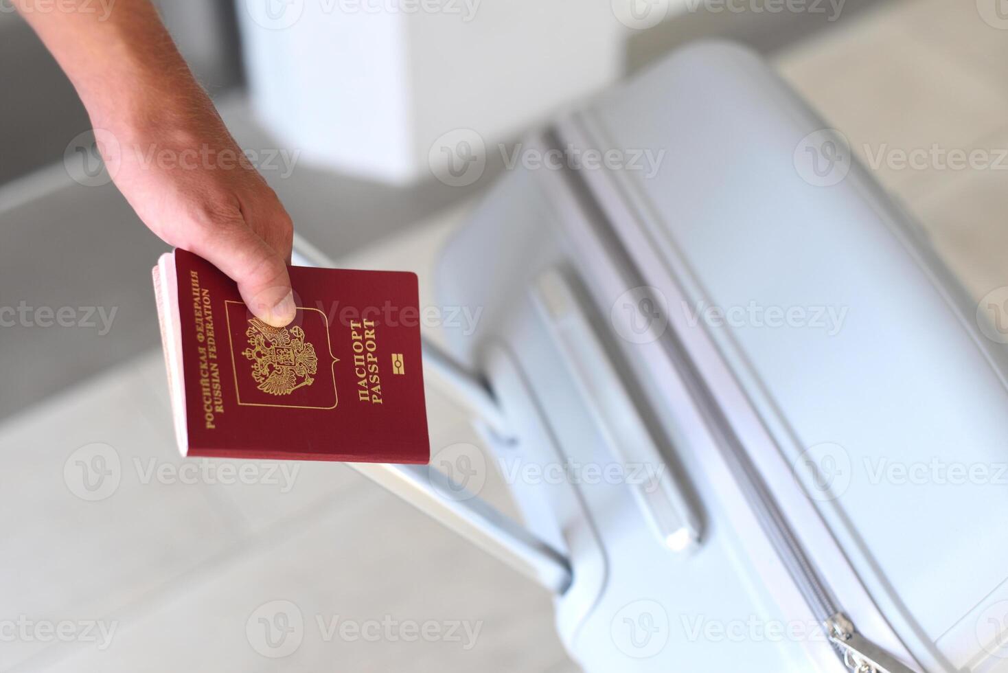A hand holding Russian passport and suitcase photo