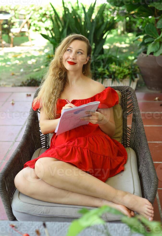 Beautiful woman artist and illustrator thinking about idea of a drawing, sitting on a couch photo