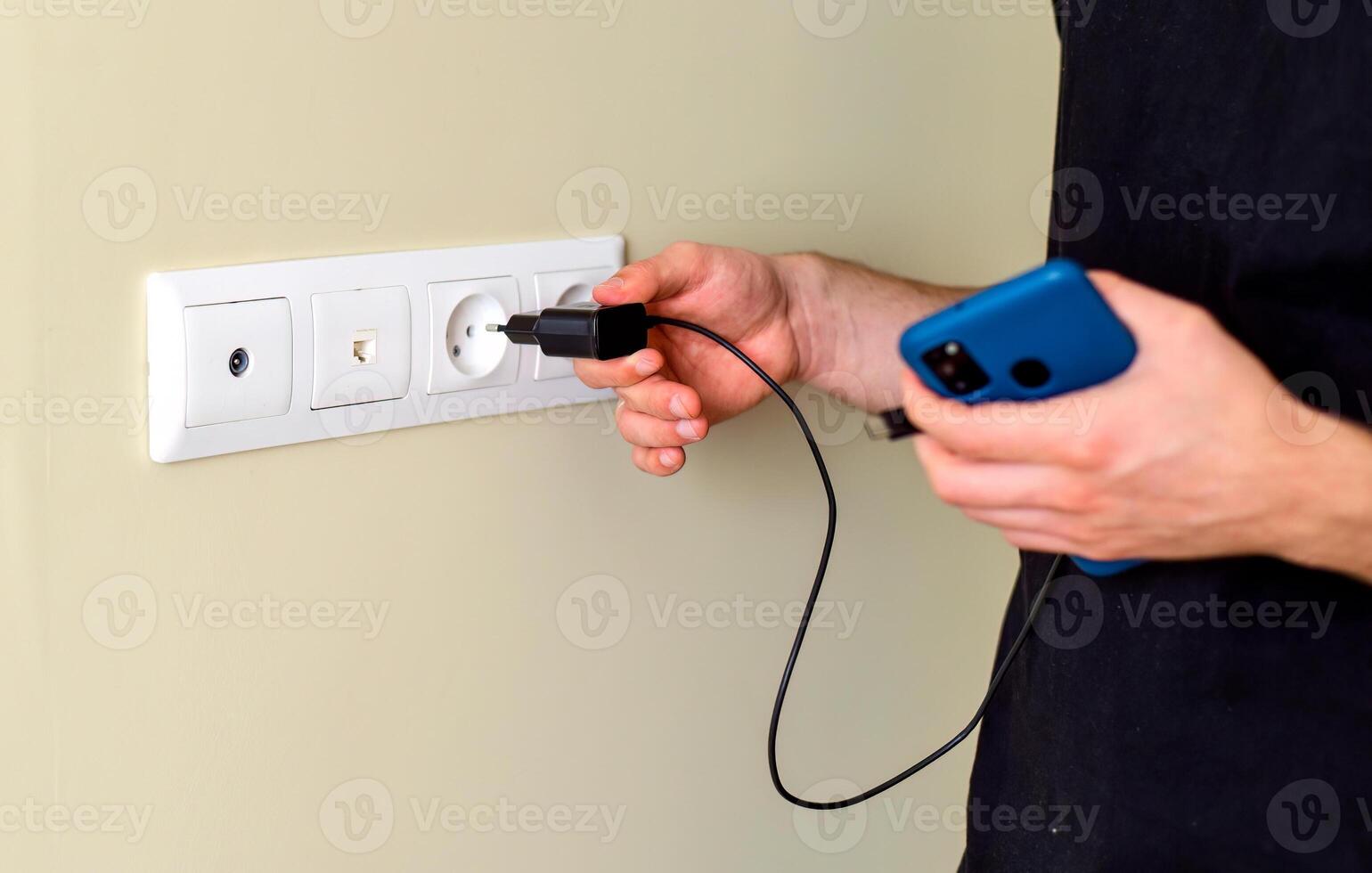 Hand inserting smarthone charger into socket photo