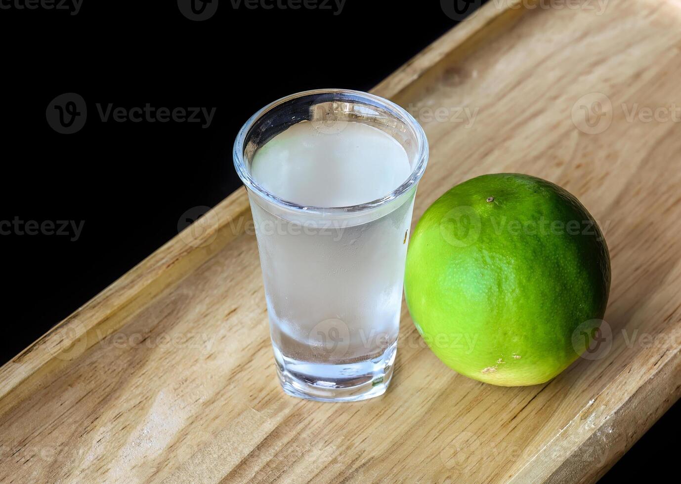Alcohol shot made of lime juice on a wooden board with with copy space photo