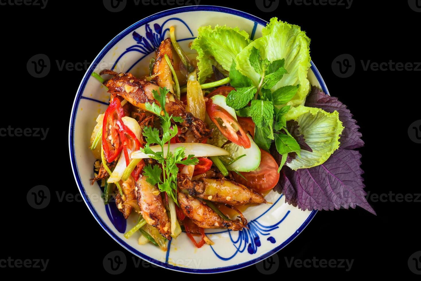Fried squid with vegetables on a black background for a menu photo