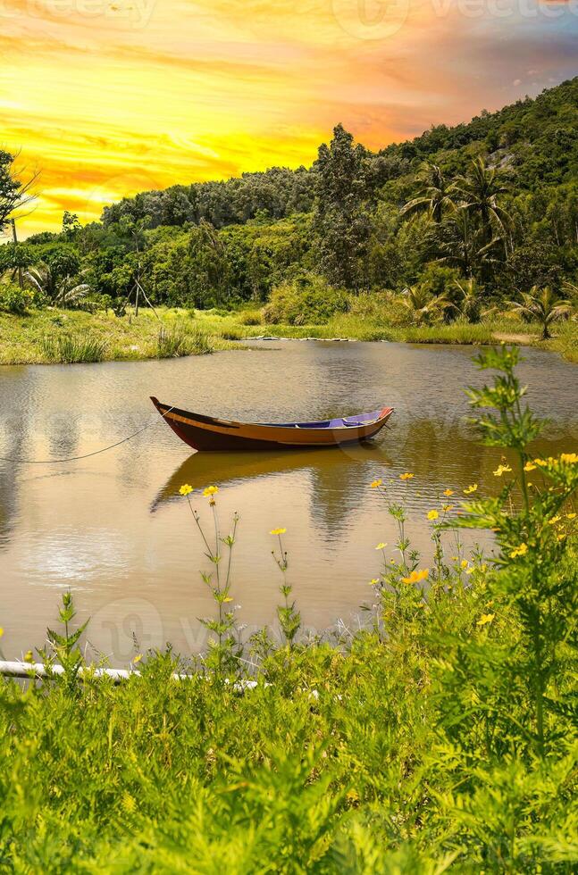 Wooden boat in on the lake among yellow flowers in Vietnam under sunset photo