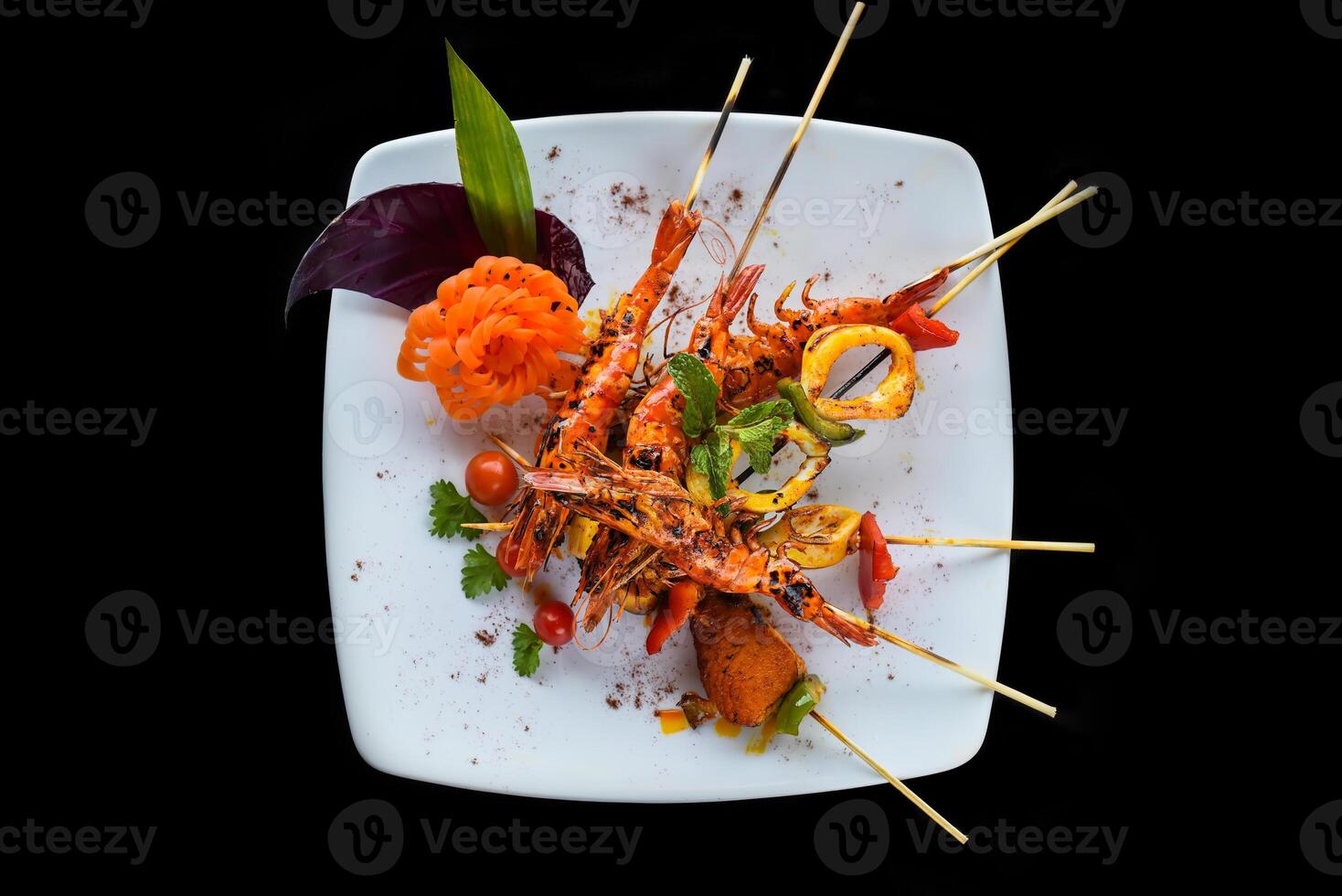 Grilled king shrimps with vegetables on white plate isolated on black background top view photo