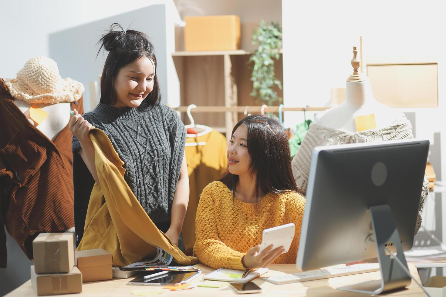 Two women are looking at a computer screen while standing in front of a desk photo
