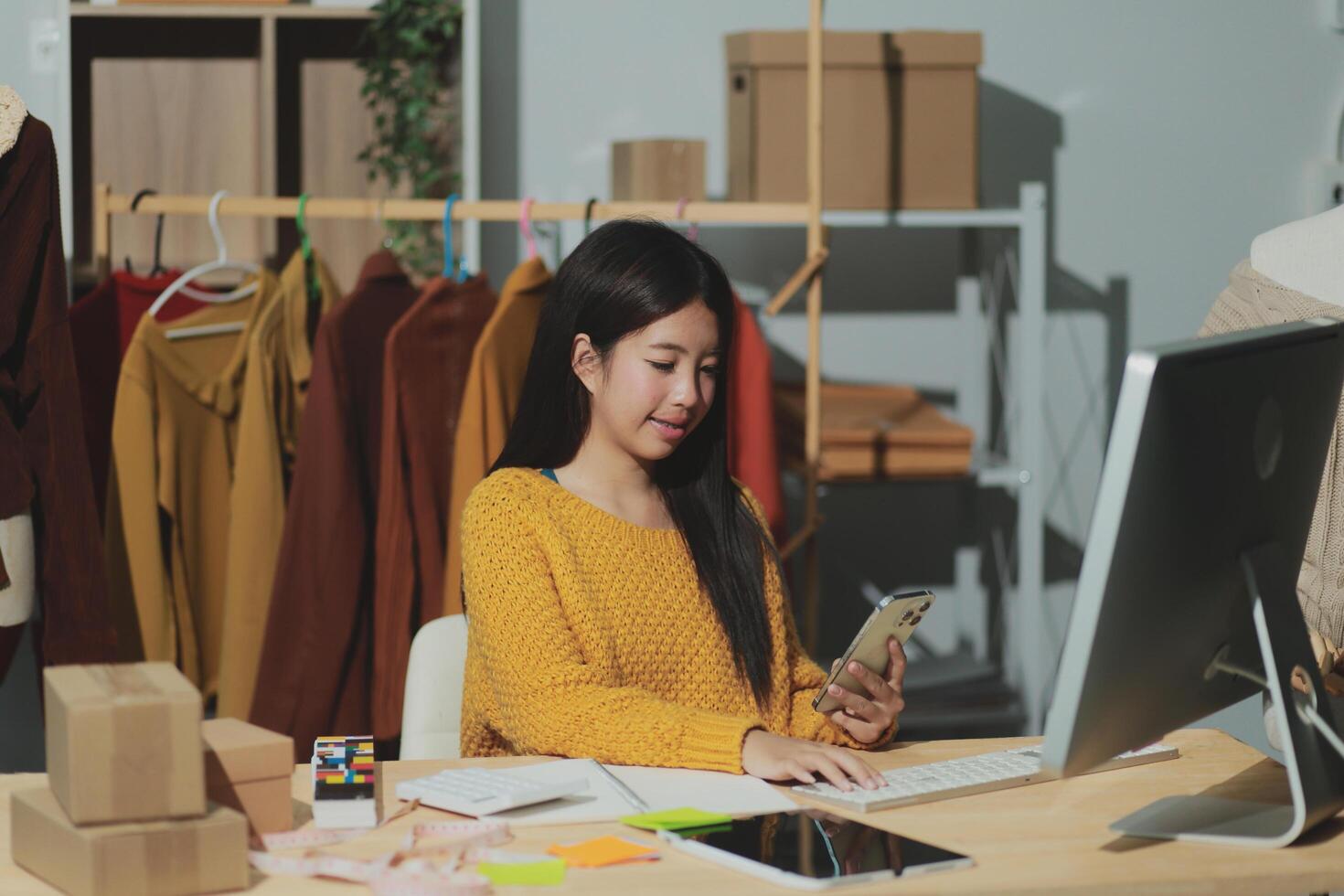 A woman is sitting at a desk with a computer and a phone photo
