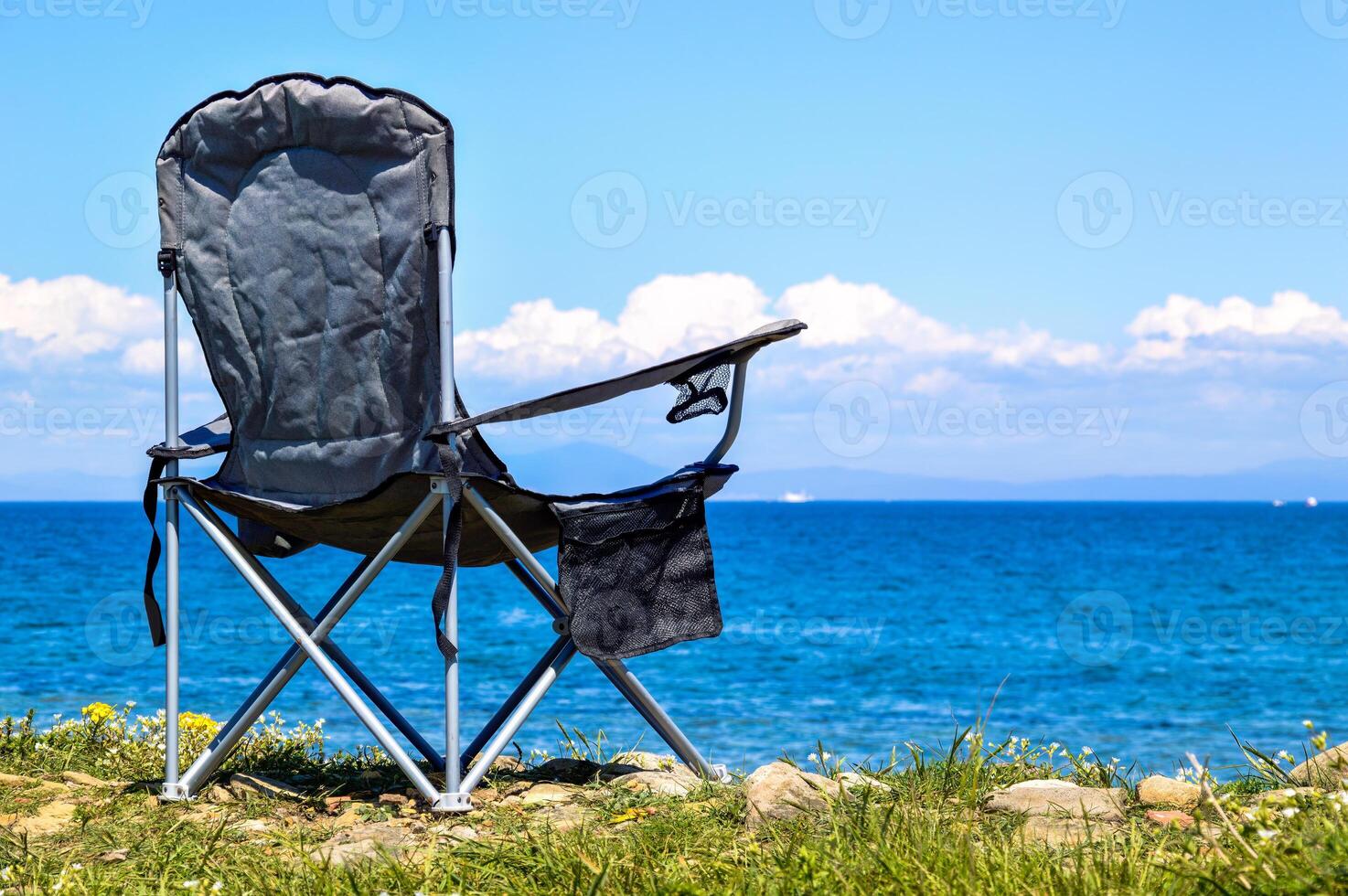Black folding tourist chair on the background of the Japanese sea without people. with copy space photo
