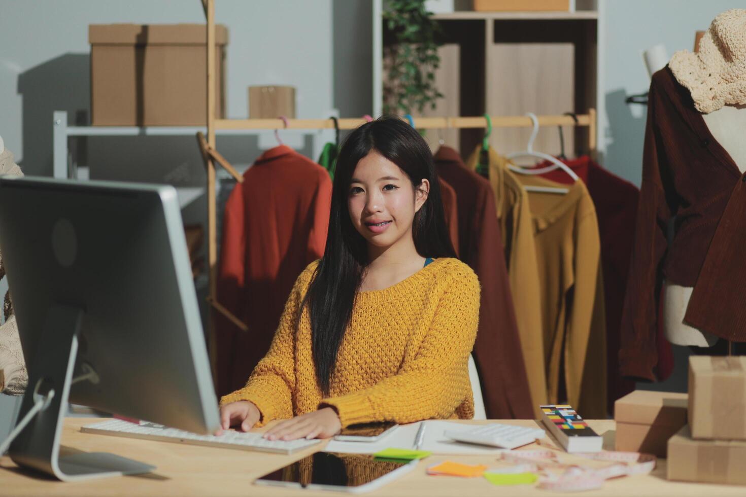 A woman is sitting at a desk in front of a computer photo