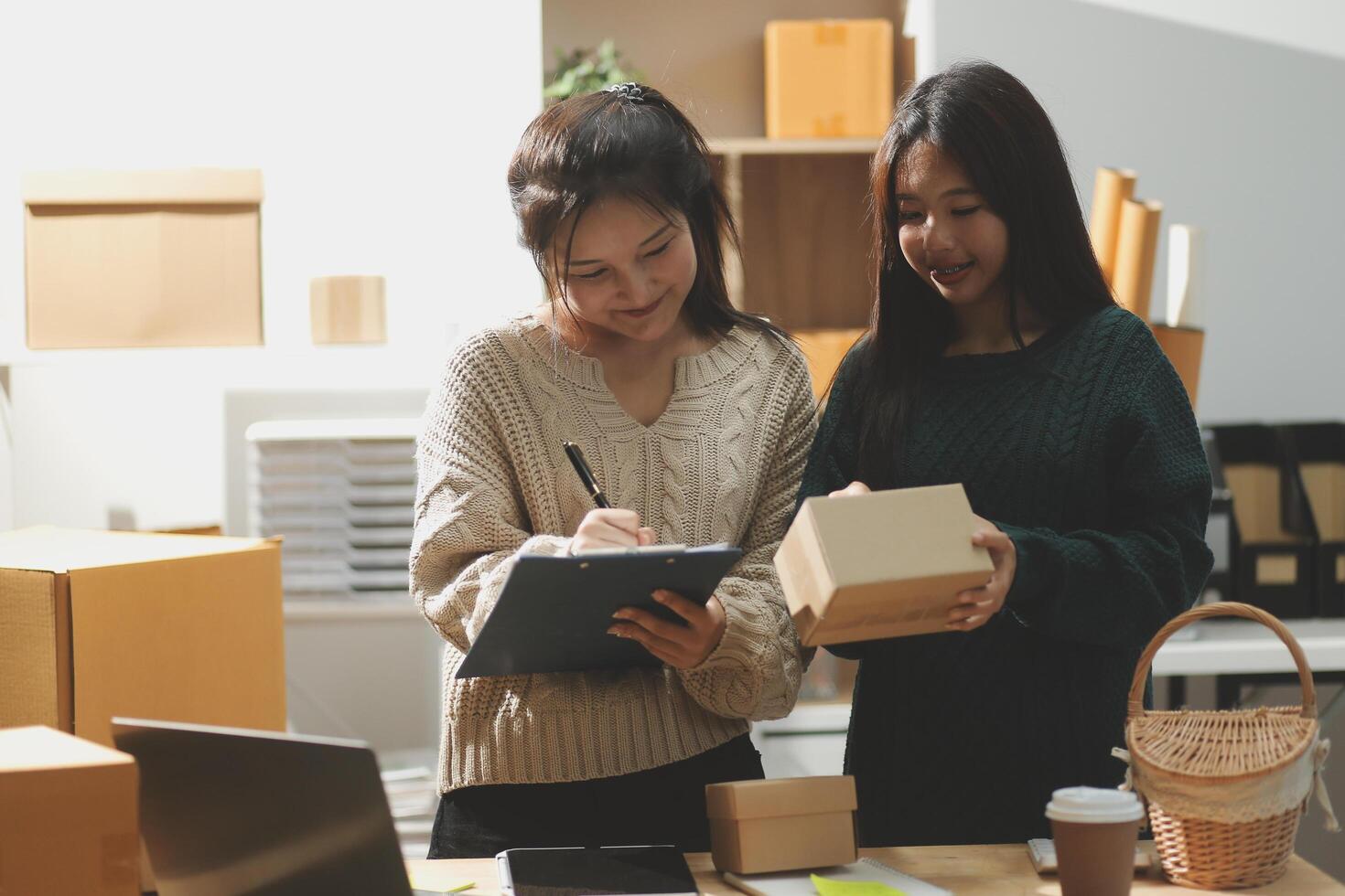 Two women standing in front of boxes and laptops photo