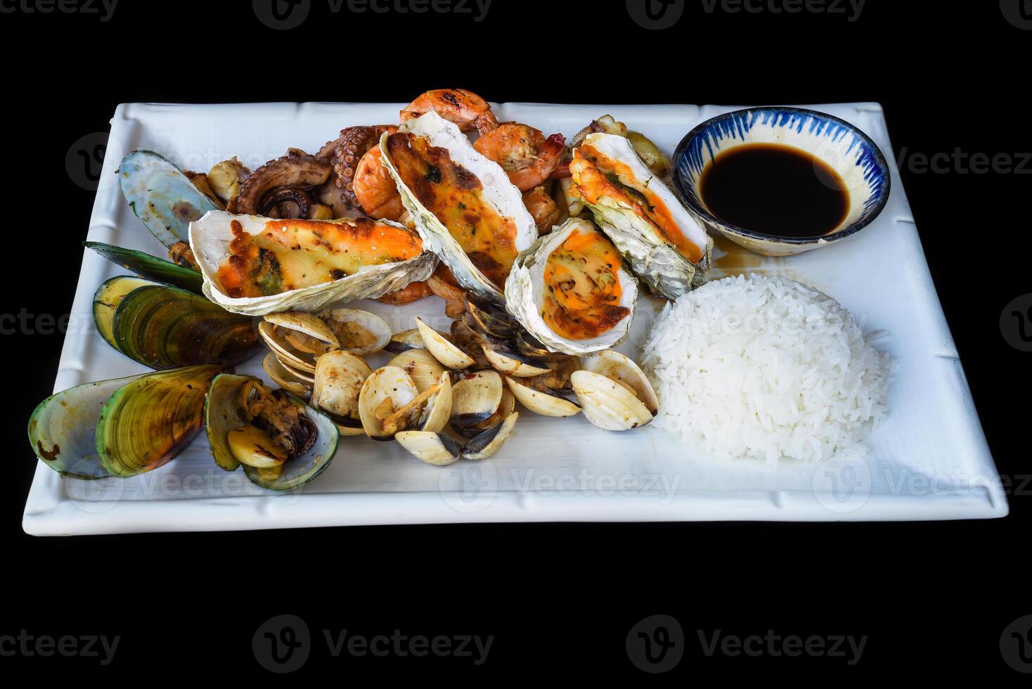 Sauteed seafood on a white plate close up isolated on a black background side view photo