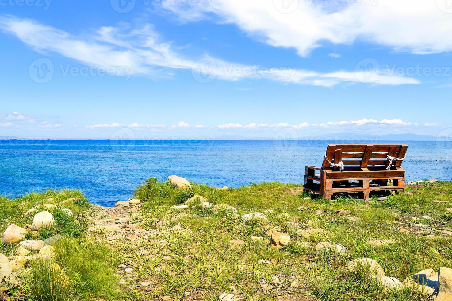 Wooden old bench without people on the background of the Japanese sea on a summer day photo