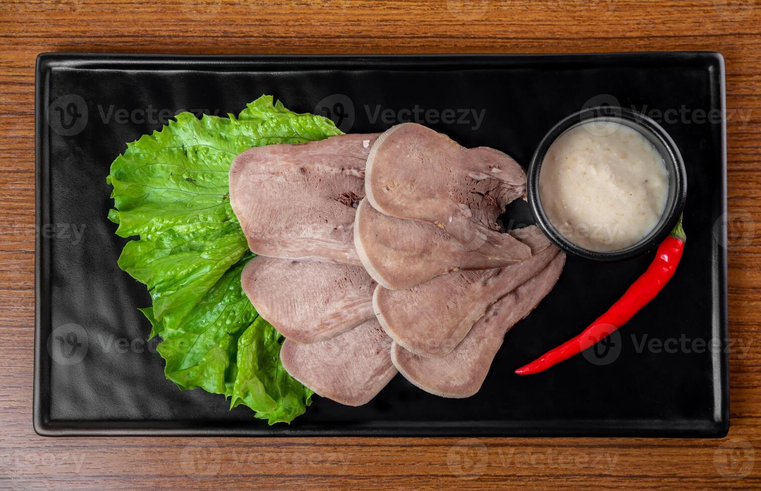 Appetizer with slices of tender beef on a black plate on a white background photo