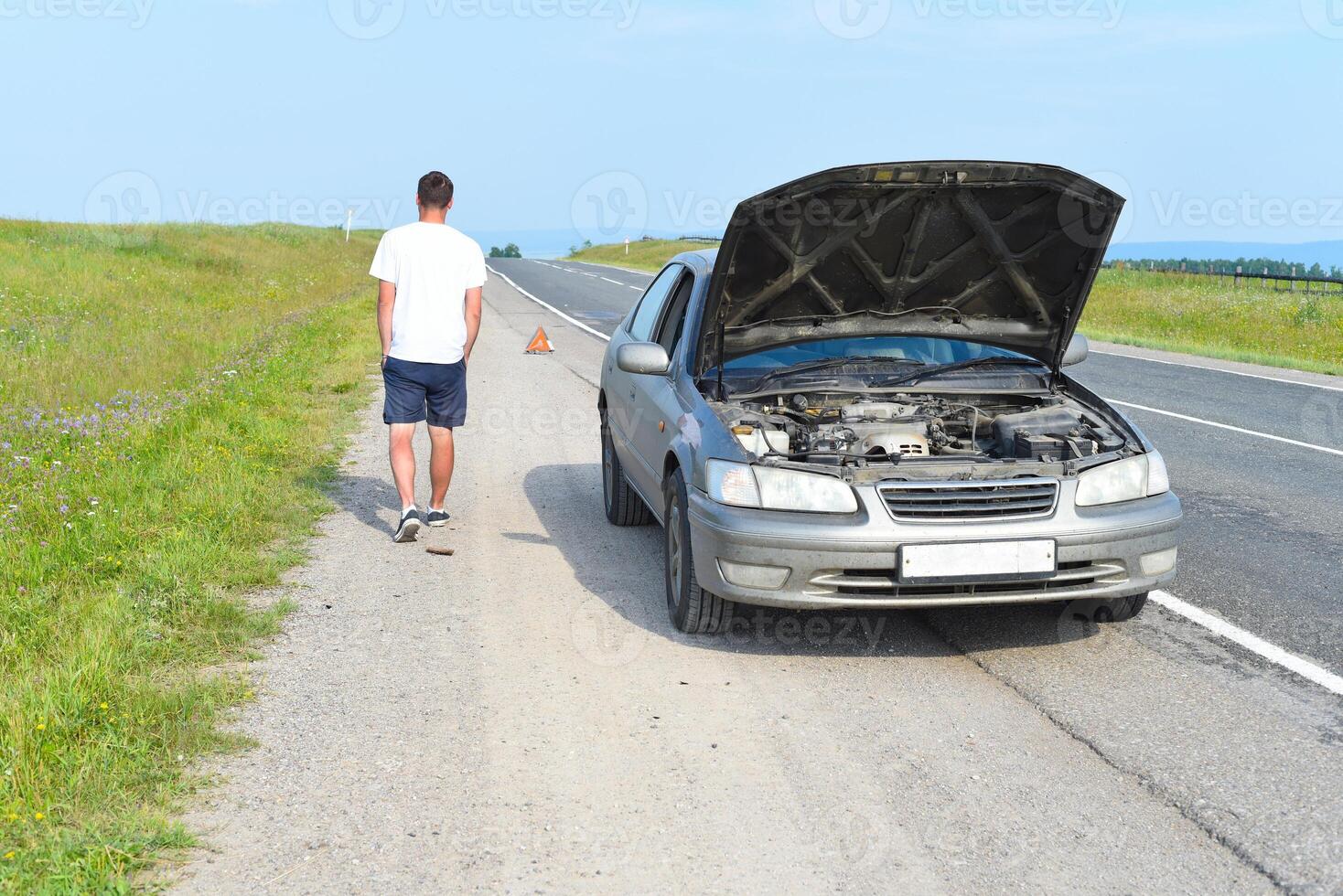Sad man near broken car searching help in field photo