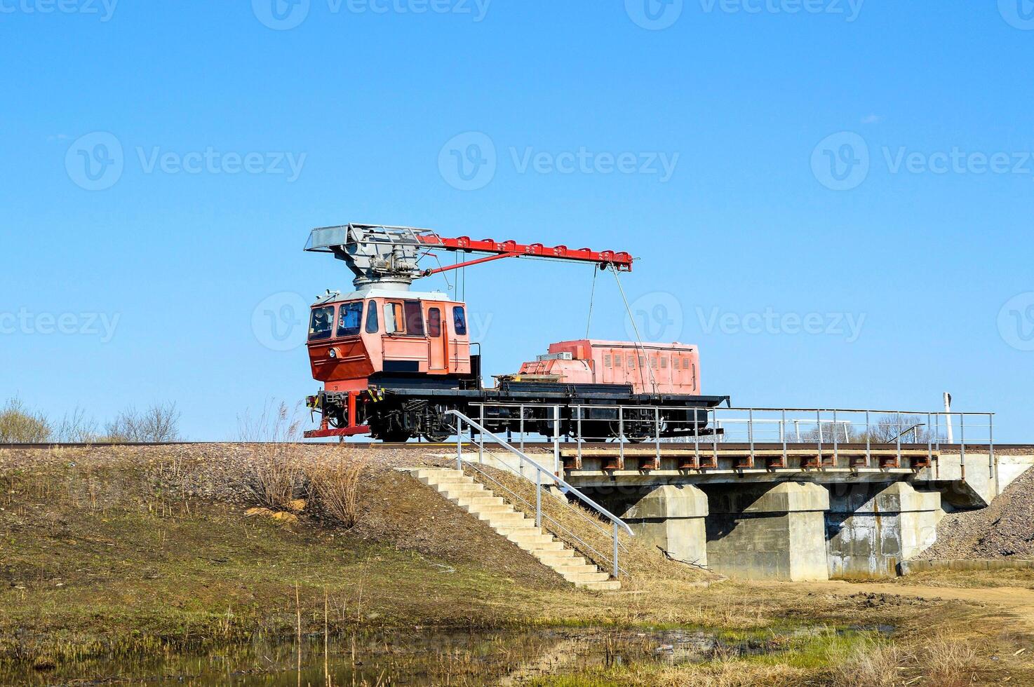 Red railroad crane on the bridge in country side photo
